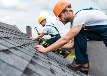 selective focus of handsome handyman repairing roof with coworker selective focus of handsome handyman repairing roof with coworker